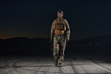 A professional soldier in full military gear striding through the dark night as he embarks on a perilous military mission