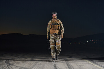 A professional soldier in full military gear striding through the dark night as he embarks on a...