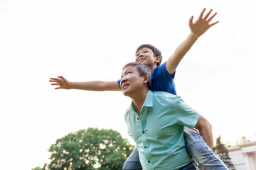 asian boy flying forward on dad's back in summer, korean senior pensioner playing with child in...