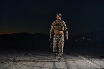 A professional soldier in full military gear striding through the dark night as he embarks on a perilous military mission