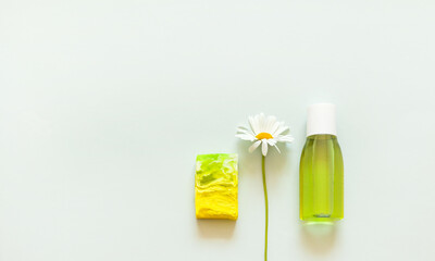 Summer hygiene products - natural handmade soap and light shampoo with chamomile extract on a light pastel background. Empty space for text. Flat lay, close-up, top view, mock up, copy space