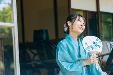 縁側でうちわを持つ浴衣姿の日本人女性
