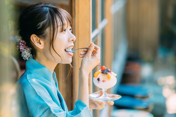 縁側でかき氷を食べる浴衣姿の日本人女性