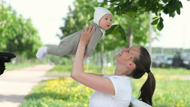 Loving young mom kisses little infant child, Mother And Baby Kissing, Happy Cheerful Family in summer park outdoor