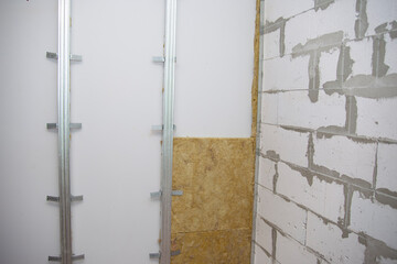 The worker insulates the walls with mineral wool for further cladding with plasterboard. Heat insulation and sound insulation of housing