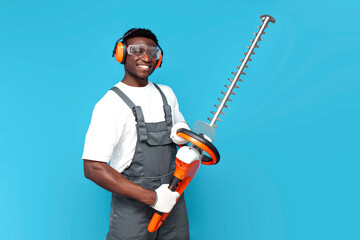 garden worker in uniform holding electric brush cutter on blue isolated background - obrazy, fototapety, plakaty