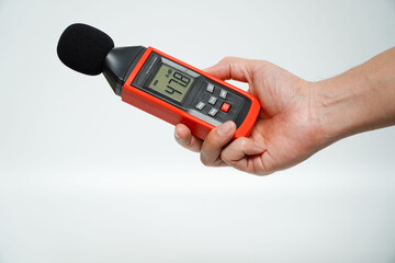 hand holding a digital sound level on a white background,Sound level meters are commonly used in noise pollution studies. - obrazy, fototapety, plakaty