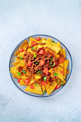 Nachos, Mexican food, tortilla chips with beef and fresh vegetables, shot from the top on a stone background