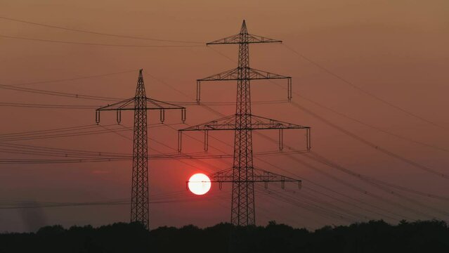 Sunset behind high-voltage pylons, time-lapse, Lueneburg, Lower Saxony, Germany, Europe