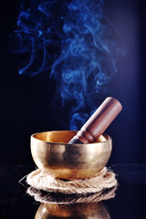 Tibetan singing bowl with stick on the black background 