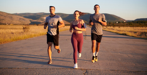 A group of young athletes running together in the early morning light of the sunrise, showcasing their collective energy, determination, and unity 