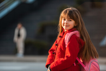 A portrait of a happy child student with school backpack outside.