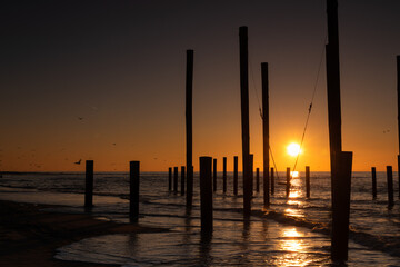 Obraz premium Monumental wooden poles, including a swing set, in the sea during a lovely sunset in the Netherlands