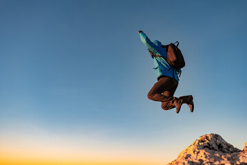 A happy man jumping on top of a mountain concept of adventure travel extreme sport hiking.