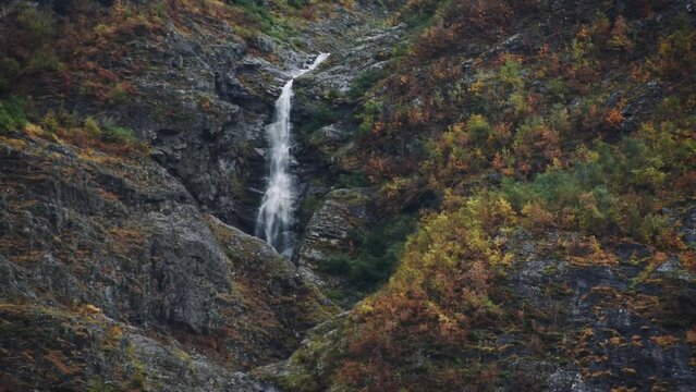 Beautiful waterfall surrounded by cliffs and an autumn coloured forest in Norway