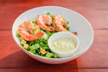 Shrimp Salad. Healthy Seafood Caesar Salad with prawns on the wooden table.