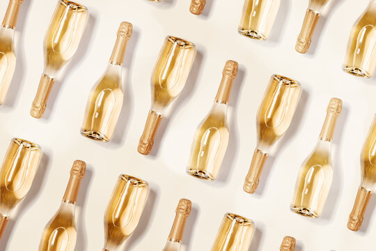 Minimal food pattern with bottles of white sparkling wine, full glass champagne bottles close up on beige. Summer alcohol drink concept. Celebrate holidays, happy summer party background