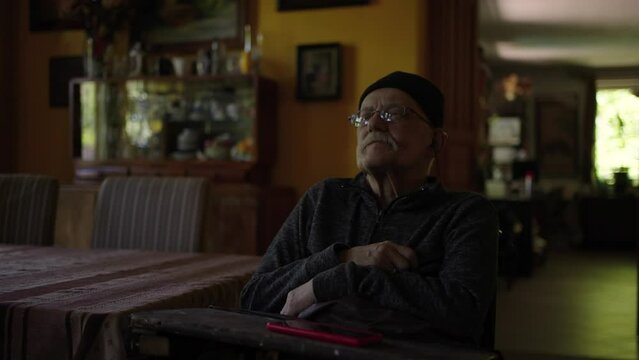 Old man in a wheelchair watching tv in the livingroom at home