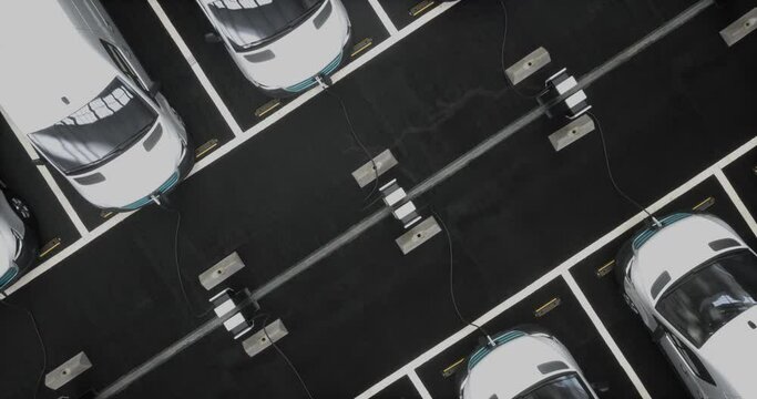 OVERHEAD Fleet of generic electric delivery vans charging on charging stations
