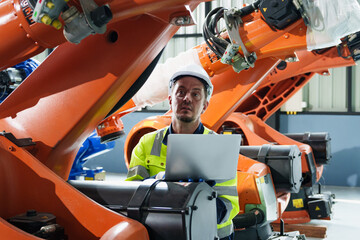 Architectural engineer use laptop checks and control automation robot arms machine in an...
