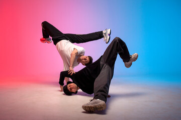 two dancer guys break dance on red blue background and do trick together, male acrobats perform...