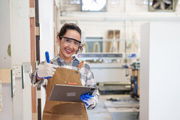 Portrait of industrial carpenter workers standing and looking at the camera with smiling and showing thumbs up in carpentry workshop factory. Production line of the wooden working industrial factory. 