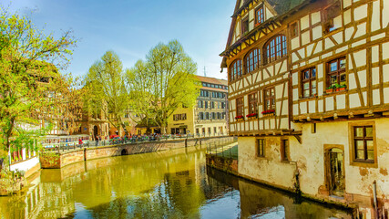 Strasbourg, France – April 9, 2011: Ancient wood-framed traditional German French houses in Strasbourg near river canal at sunset colors, historical downtown of the city