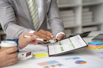 Group of business people meeting to plan, think, analyze, point to graph and business growth to plan new business expansion in the future using a laptop and a calculator.