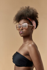 Portrait of young, stylish, beautiful, african woman in top and trendy sunglasses against studio background
