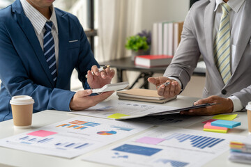 Businessmen use a calculator to calculate company financial statements for their colleagues, view and jointly solve problems within the company. Business finance and accounting concepts