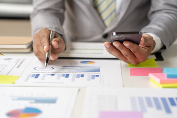 Group of business people meeting to plan, think, analyze, point to graph and business growth to plan new business expansion in the future using a laptop and a calculator.