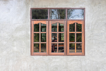 A gray concrete wall background decorates an old wooden glass window.