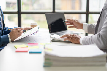 Businessmen use a calculator to calculate company financial statements for their colleagues, view and jointly solve problems within the company. Business finance and accounting concepts