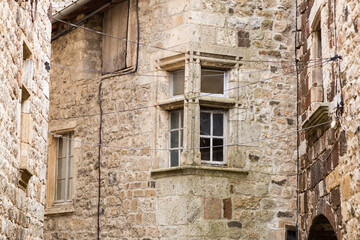 Fototapeta na wymiar Belle fenêtre à meneaux d'angle moulurés dans un vieux village en pierres. Thueyts, Ardèche