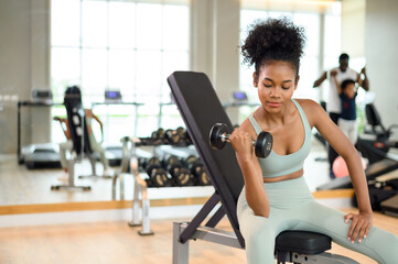 Sporty fitness African American woman working out with dumbbells strength and strength endurance at the gym.