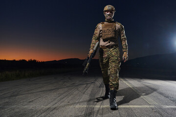 A professional soldier in full military gear striding through the dark night as he embarks on a...