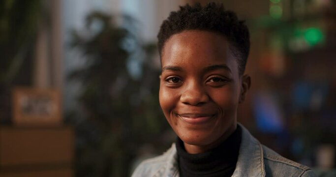 African lady donning trendy pink sunglasses, showcasing her radiant smile looks directly into camera expression suggests friendly approachable demeanor making ideal candidate for socializing engaging.