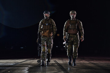 Two professional soldiers marching through the dark of night on a dangerous mission, epitomizing their unwavering bravery, unwavering teamwork, and the high-stakes intensity of their specialized