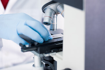 The scientist working in the laboratory is using a microscope.