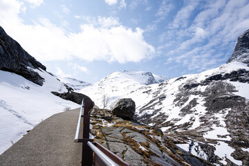 now on the mountain and the rocks are gray but above them there is a blue sky with white clouds and...
