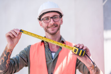 White man engineer prepares measure tape device to inspect the construction work on site.