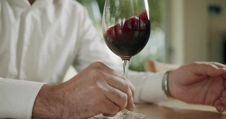 Winemaking concept. Man winemaker tasting wine. Sommelier is shaking the glass of wine and tasting it. Elegantly dressed man is tasting a flavor and drinking fresh red wine poured in transparent glass