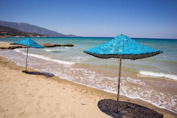 Calm beach with blue straw umbrellas with turquoise sea