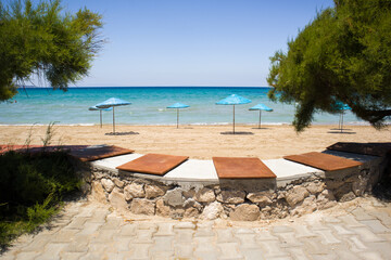 Calm beach with blue straw umbrellas with turquoise sea