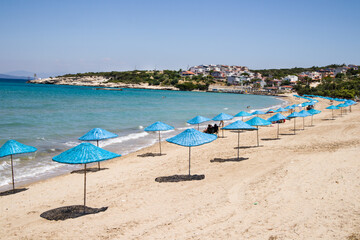 Calm beach with blue straw umbrellas with turquoise sea
