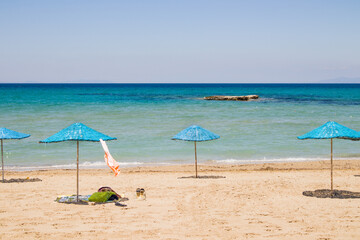 Calm beach with blue straw umbrellas with turquoise sea