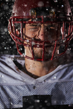 American Football Field: Lonely Athlete Warrior Standing on a Field Holds his Helmet and Ready to Play. Player Preparing to Run, Attack and Score Touchdown. Rainy Night with Dramatic Fog, Blue Light