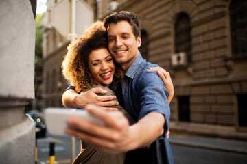 Young couple taking a selfie while walking on a city street