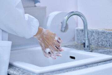 Doctor washing hands at faucet to clean bacteria or virus on his hand  in the hospital.