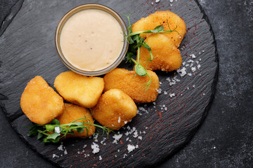 Fried nuggets with sauce and herbs on a black stone
